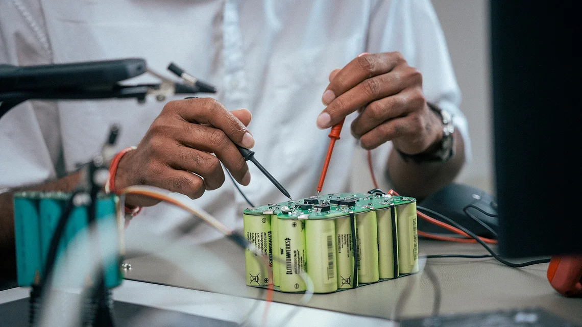 Techniker misst mit Prüfspitzen an einem Batteriemodul aus zylindrischen Zellen auf einem Labortisch.